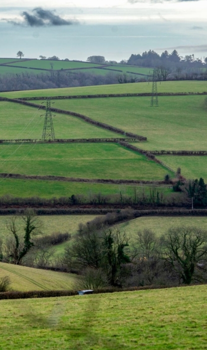A rural landscape in mid-Wales with overground power lines.