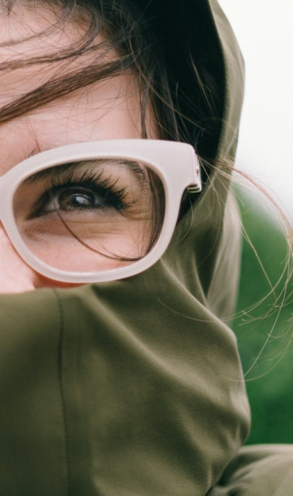 A close-up of a person wearing glasses and a raincoat.