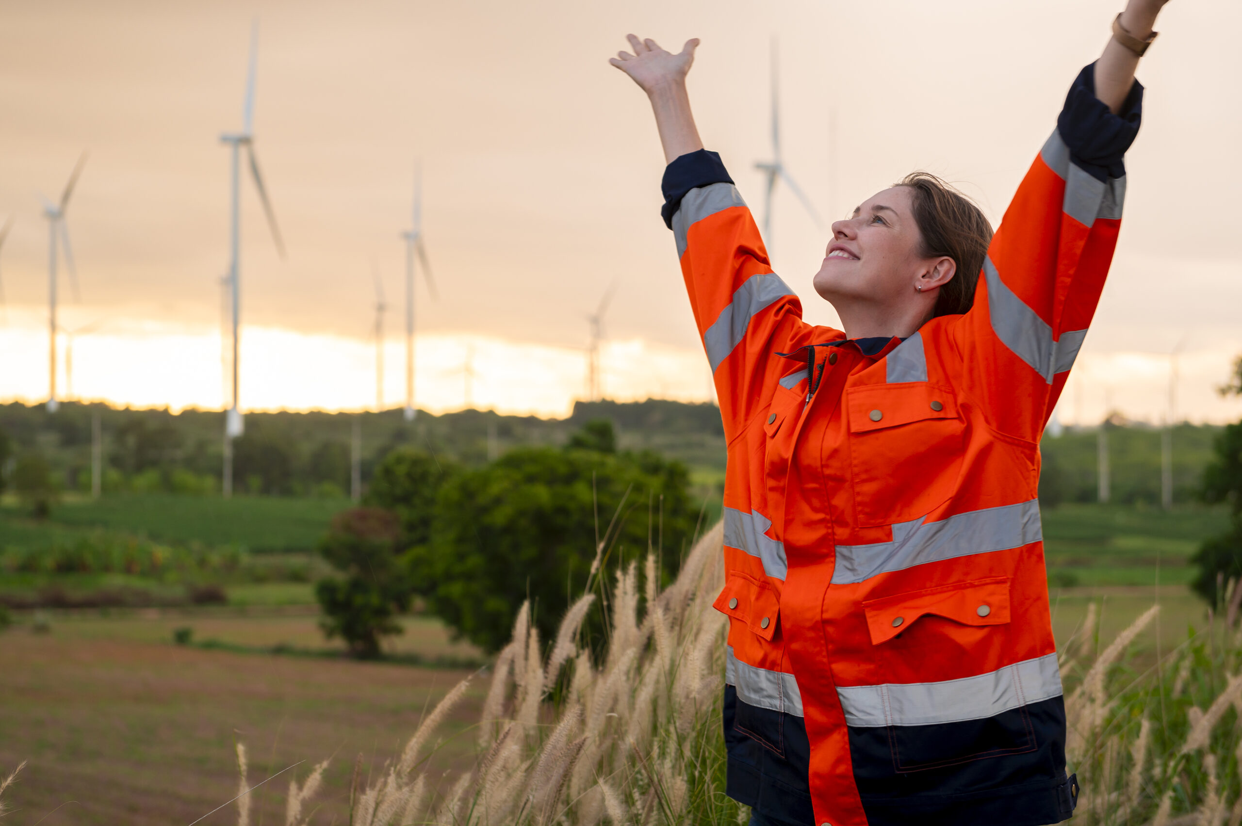 Smart engineer with protective helmet rising hands up at electrical turbines field